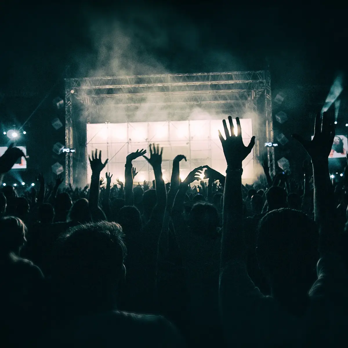 A big crowd raising their hands at a music concert.